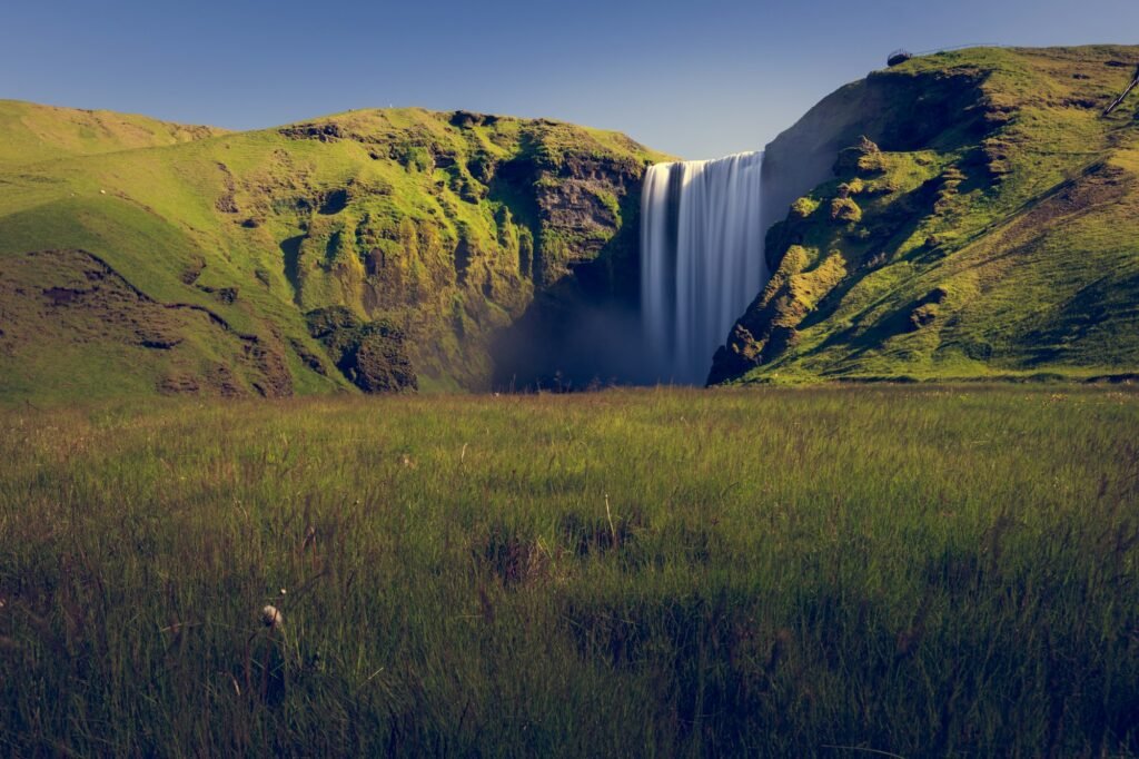 Skógafoss waterfall pouring over a green cliff on Iceland's South Coast