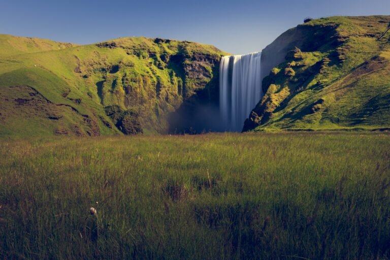 Skógafoss waterfall pouring over a green cliff on Iceland's South Coast